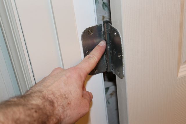 arreglar una puerta que se cierra o se abre sola, Retire el pasador de la bisagra del medio o de la bisagra inferior