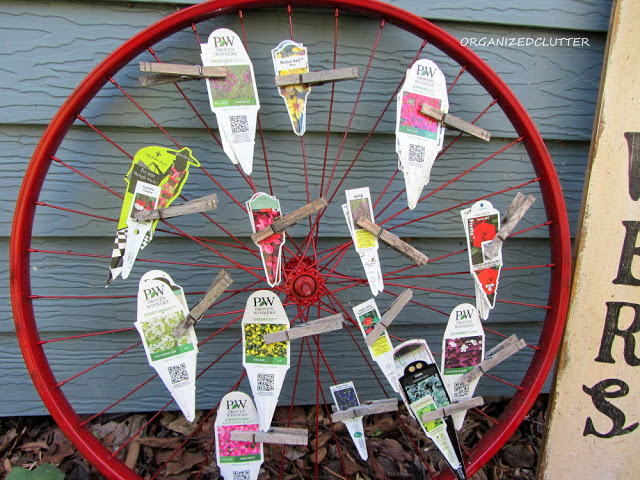 an up cycled bicycle wheel garden pumpkin, crafts, repurposing upcycling, seasonal holiday decor, Plant tag organizer in red during the summer