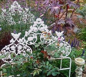 bedtime in the flea market garden, flowers, gardening, repurposing upcycling, Audrey Osborn says This is my bedroom garden a white iron bed filled with flowers The Copper castor bean plant is watching over the area