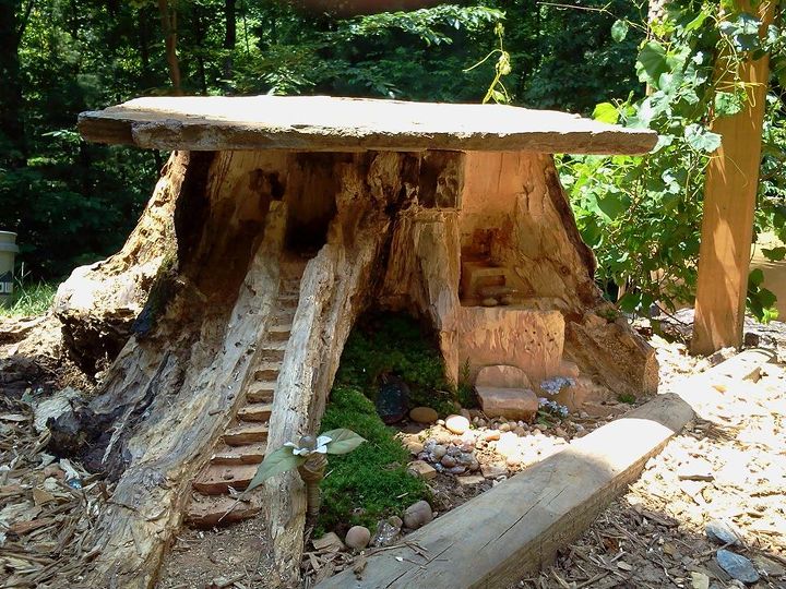 making a fairy home from an old stump, gardening, outdoor living, A little more added on the door is temporary until I find or make a round hobbit door It s a campfire and a bar above the bench I have a hole where a slide will go to ride into the lake I will create on the next bend