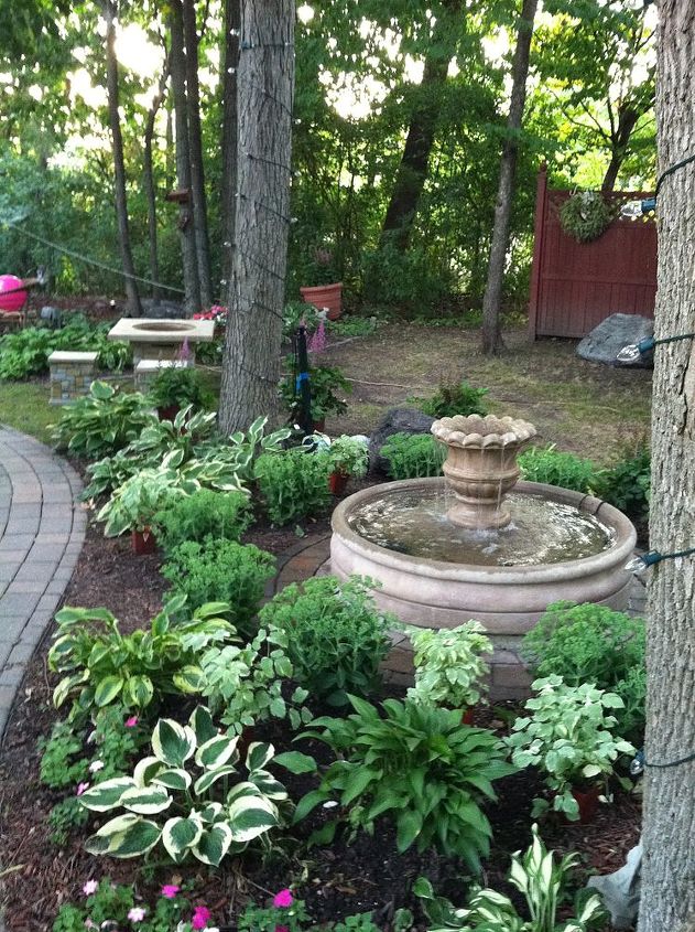 this is one of many favorite sitting spots in our backyard sanctuary that my husband, decks, gardening, outdoor living, patio, Fountain nestled among the garden of Hostas sedum snow on the mountain astible ferns