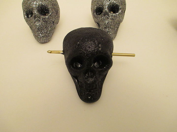 super easy dollar tree glitter skull garland, crafts, halloween decorations, seasonal holiday decor, Take a crochet hook and poke it all the way through temples of the skull