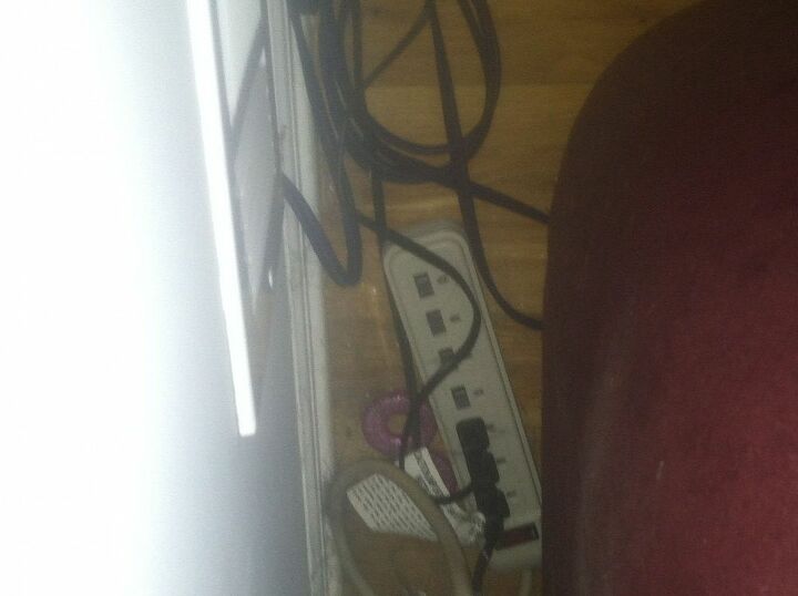 q problemas de seguridad electrica en el hogar, M s enchufes con cables por todas partes detr s de un sof Obs rvese el cable que entra en la pared justo debajo del conducto de aire