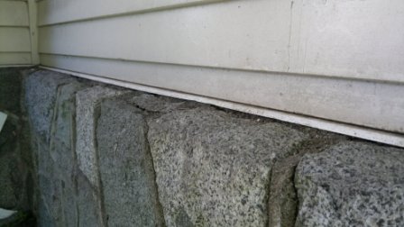 protecting junction siding meets stone wall, vertical siding comes down to meet top surface of granite stone wall