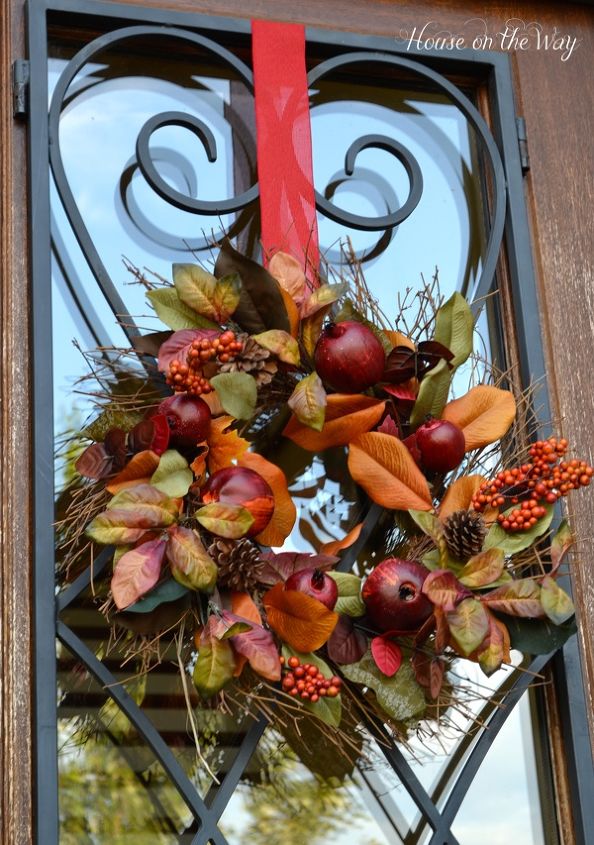 fall porch tour, porches, seasonal holiday decor, wreaths, For my front door I used this gorgeous wreath made with magnolia leaves pomegranates berries and pinecones I also used more of the red burlap ribbon as a hanger for the wreath