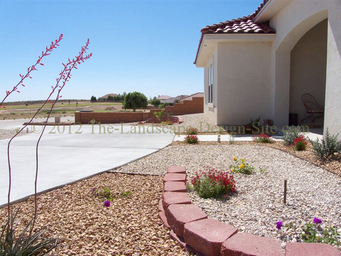 desert southwest landscaping on a small hillside circular driveway using retaining, Again this small retaining wall doesn t have any purpose of holding a slope but rather creates continuity and unity with the rest of the landscaping by adding the retaining wall element If you look closely you can see that this wall lines up with the other wall on the other side of the sidewalk to help create the continued unity as though they would meet in the middle