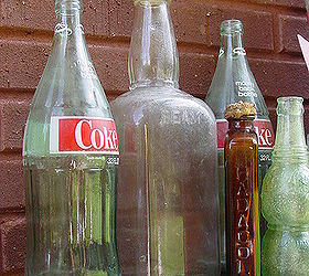 a stroll to my potting area with camera in hand, gardening, outdoor living, repurposing upcycling, The Coke bottles liquor bottle are from my picking adventure I dug the two small ones out of the ground while digging a hole for a plant The green one is a Nu Grape bottle Anyone remember those