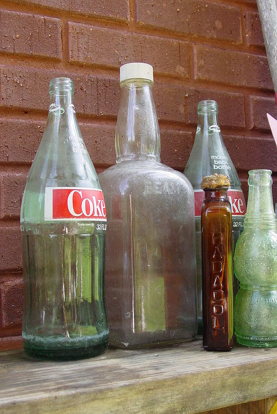 a stroll to my potting area with camera in hand, gardening, outdoor living, repurposing upcycling, The Coke bottles liquor bottle are from my picking adventure I dug the two small ones out of the ground while digging a hole for a plant The green one is a Nu Grape bottle Anyone remember those