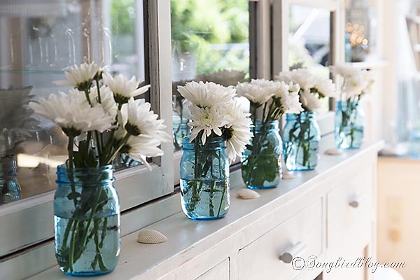 a bit of nautiical decorating with blue mason jars and flowers, home decor, Line up a row of mason jars add some flowers and sprinkle in some shells and your done