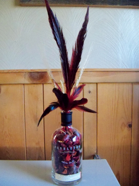 how to repupose a pendleton whiskey bottle, repurposing upcycling, filled red potpourri added red black pheasant feathers and some wheat