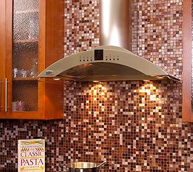 when our homeowner asked tri lite builders to redesign the kitchen to make it more, home decor, home improvement, kitchen backsplash, kitchen design, kitchen island, The backsplash for the range was created with thousands of multi colored unique glass tiles in various blended shades to create this beautiful feature wall Numbered for placement these tiles with hand applied 24 karat gold leaf between two layers of glass give a dark to light effect The backsplash goes up the wall and highlights the sleek European style stainless steel range hood with four halogen lamps that extends down from the ceiling while also complementing the cabinetry on both sides