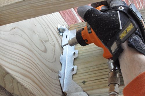 how to build a deck, decks, woodworking projects, Using a palm nailer to secure joist hangers