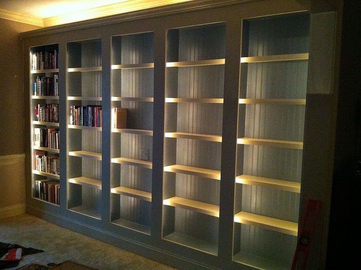 a new library, home decor, shelving ideas, The shelves are done It We painted them the same color as the house trim BEHR sensible hue Here we re loading the library shelves The in built lighting really shines here