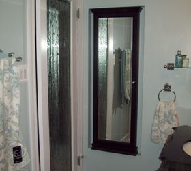 spa blue bathroom makeover on a budget, bathroom ideas, home improvement, tiling, The AFTER area behind the door I added a glass door with bamboo glass and a jewelry armoire which is recessed into the wall It provides a full length mirror and a place to keep all my jewelry organized I love it