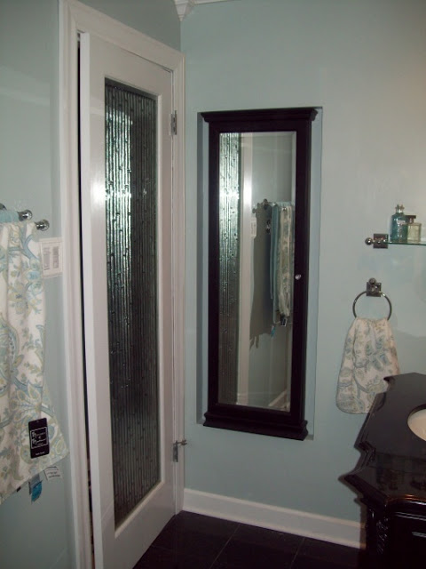 spa blue bathroom makeover on a budget, bathroom ideas, home improvement, tiling, The AFTER area behind the door I added a glass door with bamboo glass and a jewelry armoire which is recessed into the wall It provides a full length mirror and a place to keep all my jewelry organized I love it